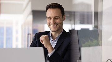 stock-photo-happy-business-executive-man-working-at-computer-at-office-workplace-typing-laughing-using-job-2598931675 1